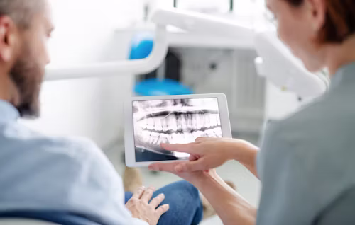 A friendly dentist explaining a 3D dental scan on a screen